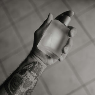 A hand holds a perfume bottle.
